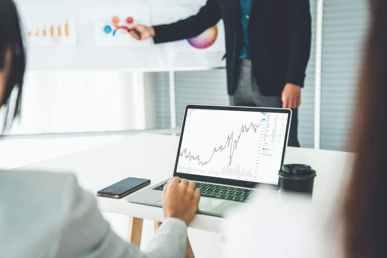 Businesswoman in analyze stock market data using laptop computer proficiently at the office while attending a group meeting with business team